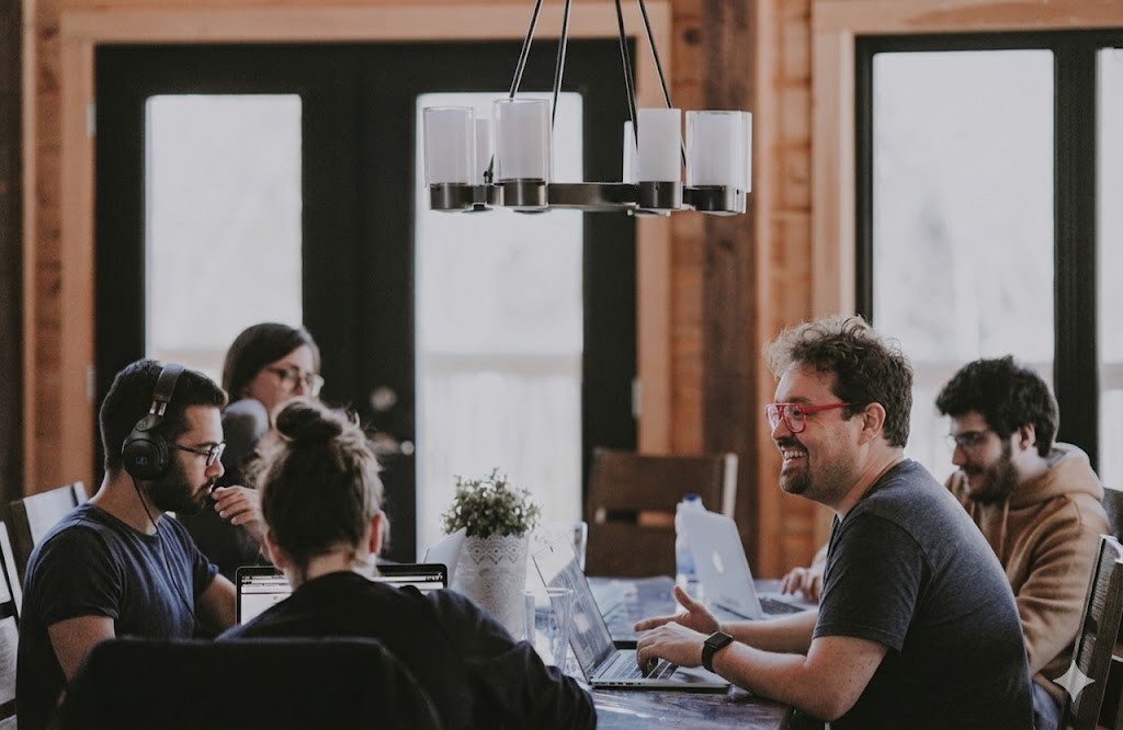 Team collaborating around a table with laptops